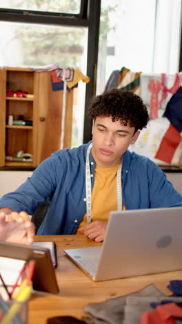 slow-motion video: biracial male designer sketches with laptop in studio