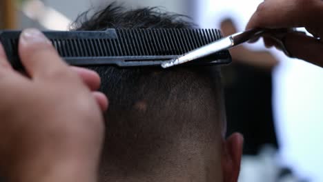A-barber-finishes-up-blending-a-fade-on-a-male-customer's-haircut