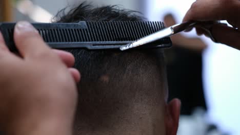 a barber finishes up blending a fade on a male customer's haircut