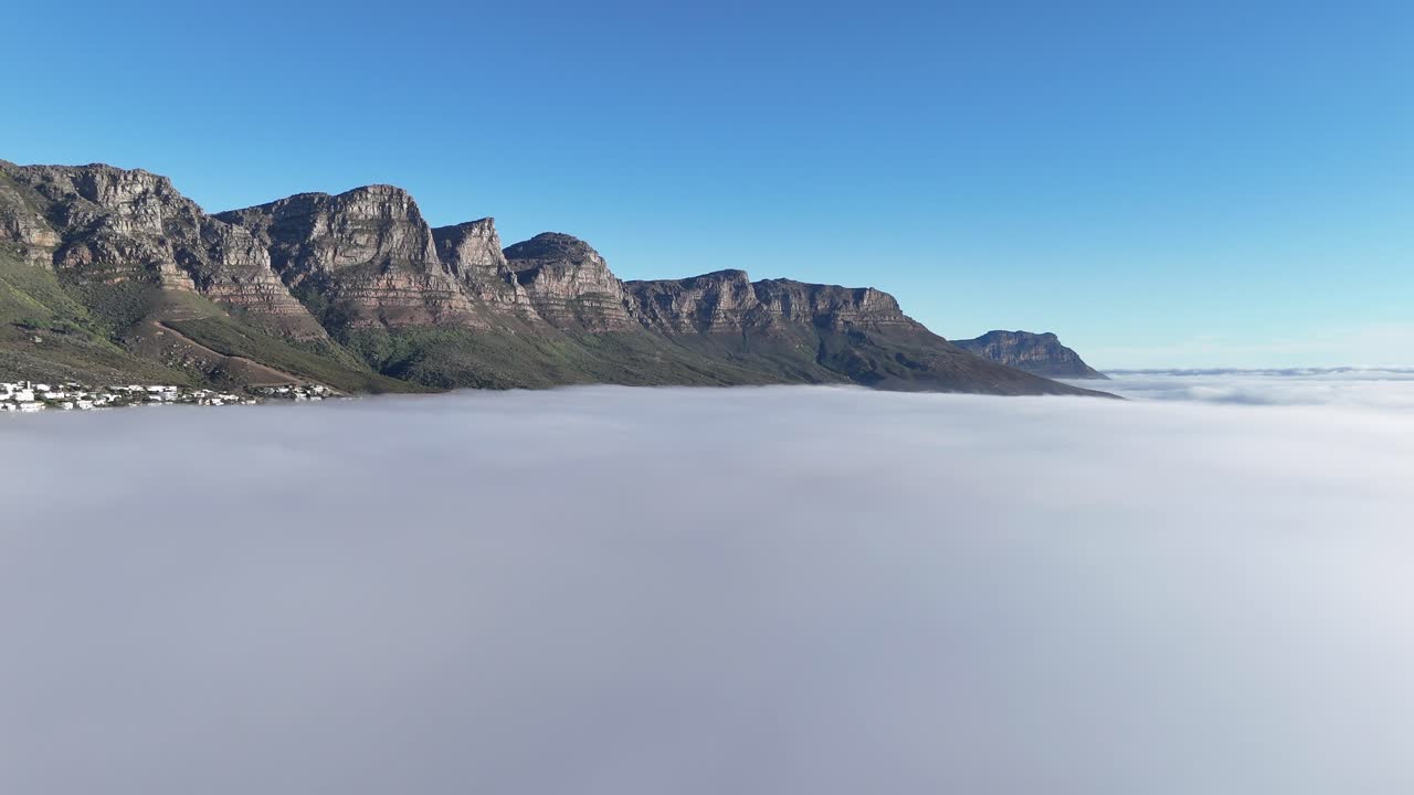 drone fly above sea of clouds with mountains emerging from fog in Cape Town South Africa