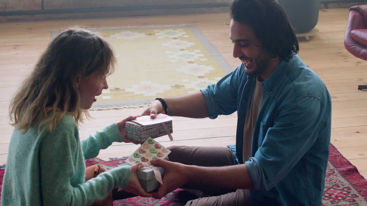feliz pareja joven sentada en la alfombra