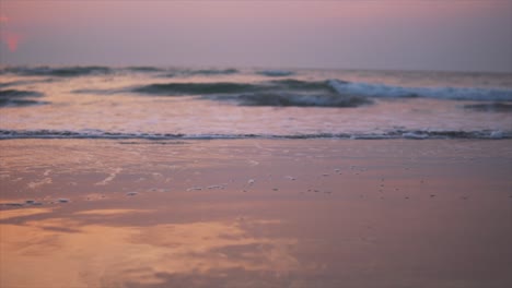 waves splashing on beautiful beach that turned orange and pink because of the sunset