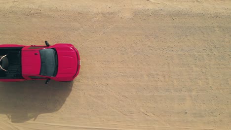 camión rojo conduciendo por una pista arenosa del desierto, entra en el marco para ver hacia abajo