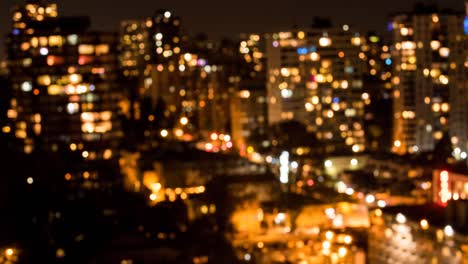 out of focus cityscape with modern buildings with lights in windows at night