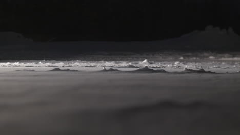 time-laps-of-closeup-of-snow-blowing-through-frozen-ground-in-darkness