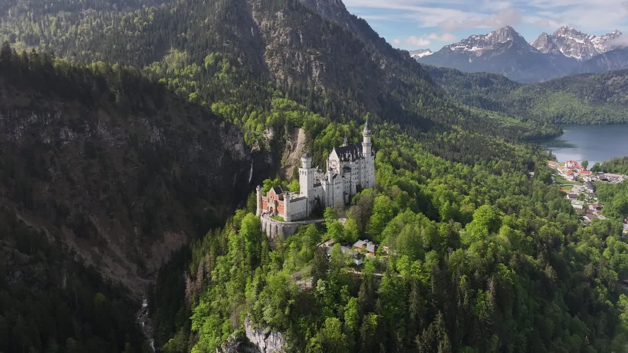 tomada aérea de un castillo blanco en medio de un bosque de montaña verde, un lago en el fondo, un hermoso paisaje