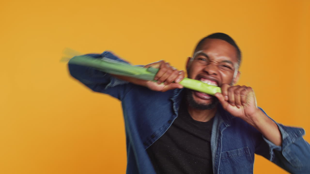Young person biting on a green onion and acting silly in studio