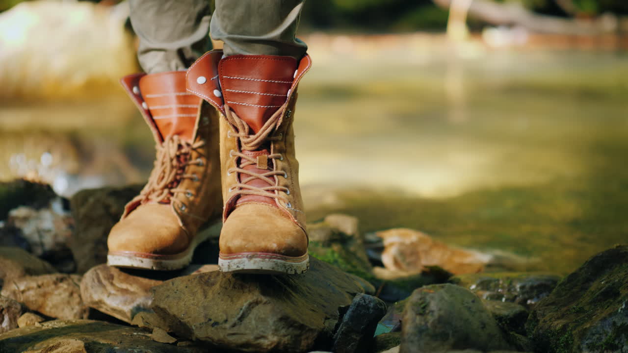 un turista con botas de trekking se encuentra cerca de un arroyo de montaña, caminatas y descanso activo