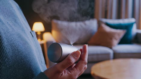 person holding a portable essential oil diffuser in a living room