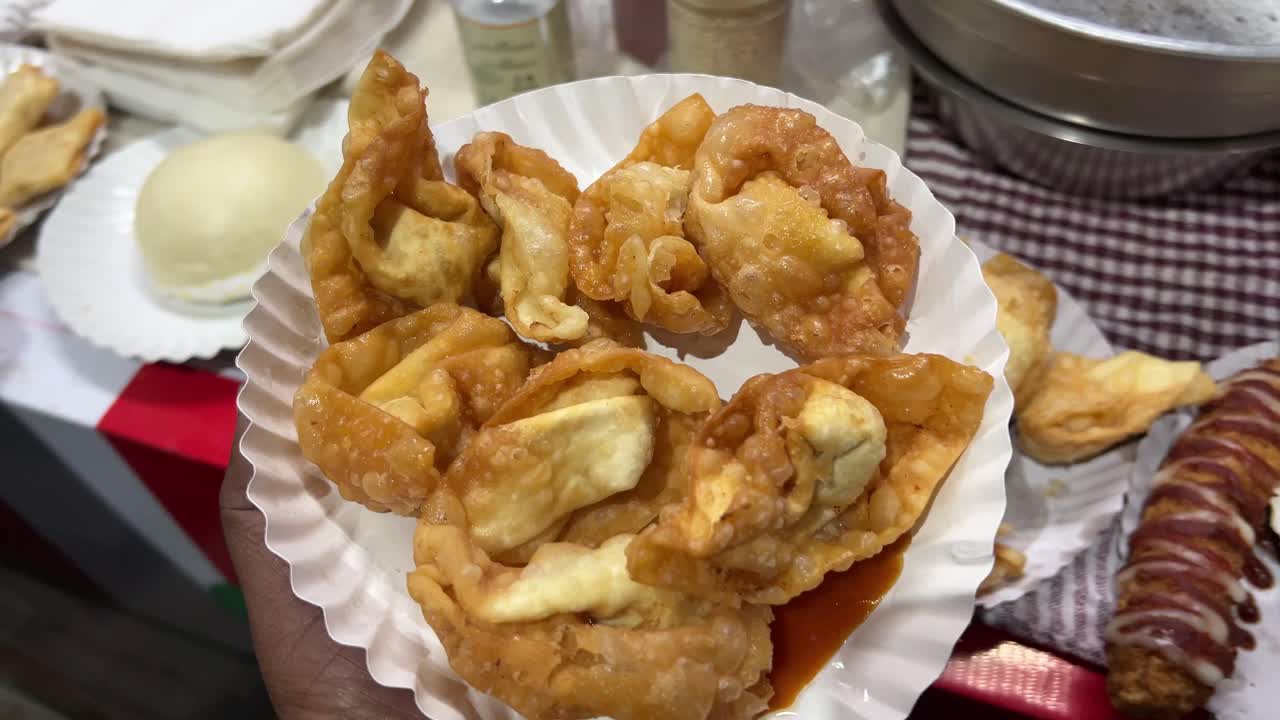 Small pieces of fried momos or chicken wanton served on disposable plate.