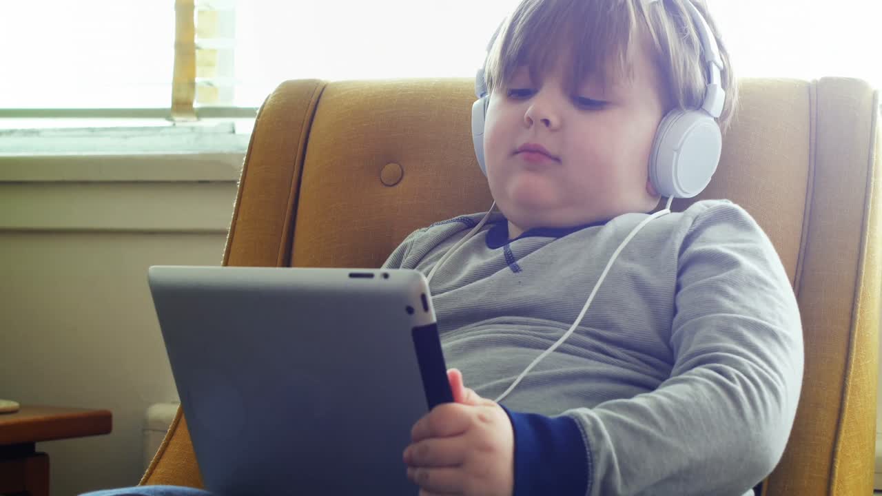 niño con auriculares usando tableta digital en la sala de estar 4k