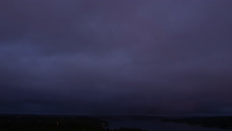 Dark-orange-and-purple-sunset,-streaming-clouds,-fading-rainbow,-aerial-hyper-lapse