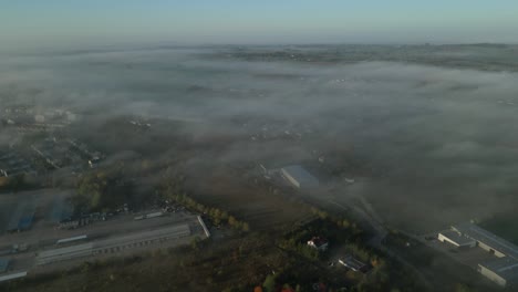 foggy rural poland in the early morning with scattered buildings and fields, aerial view