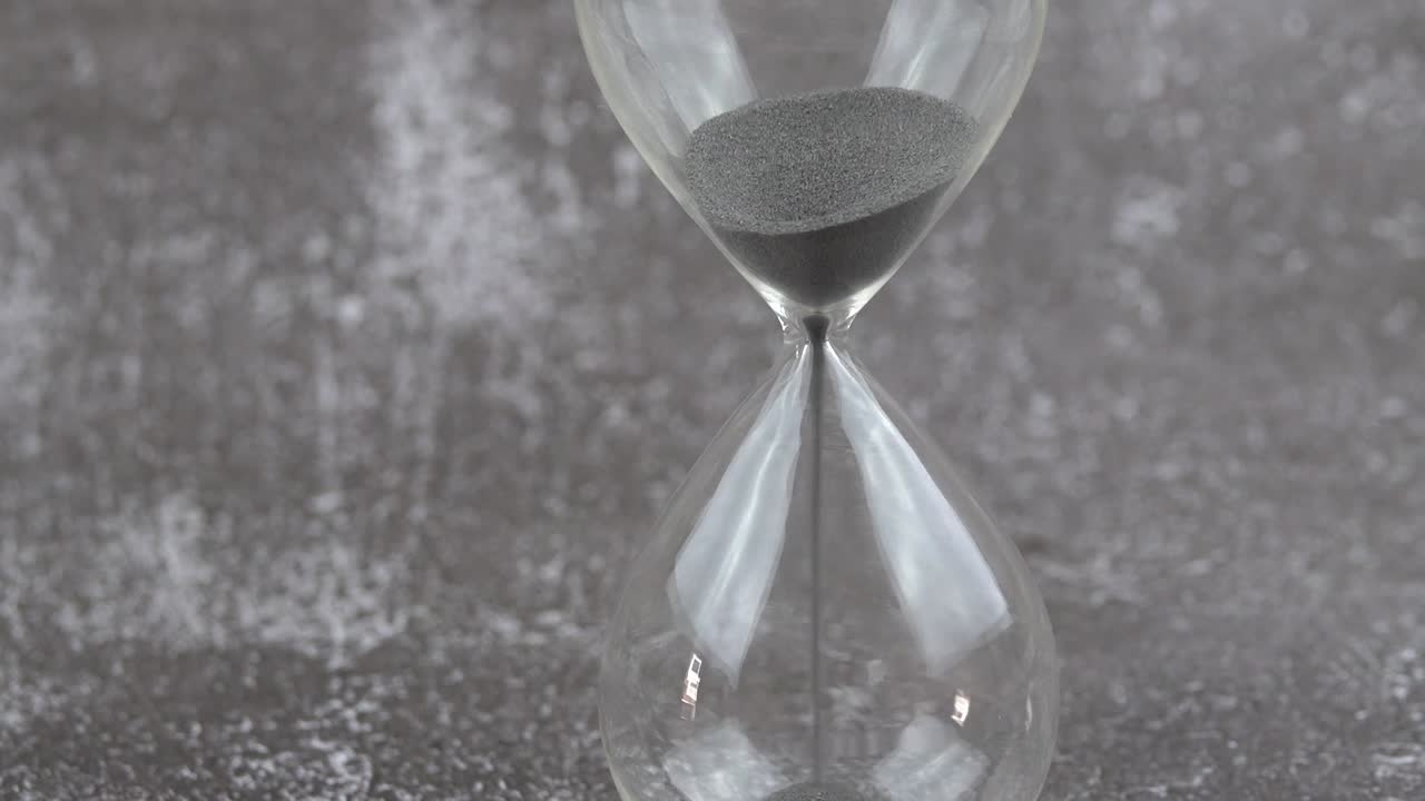 Hour glass with sands flowing through the stem