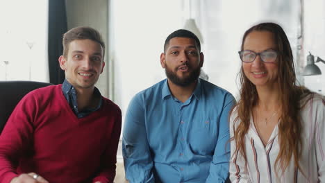 Smiling-people-sitting-in-office-and-talking-to-camera.