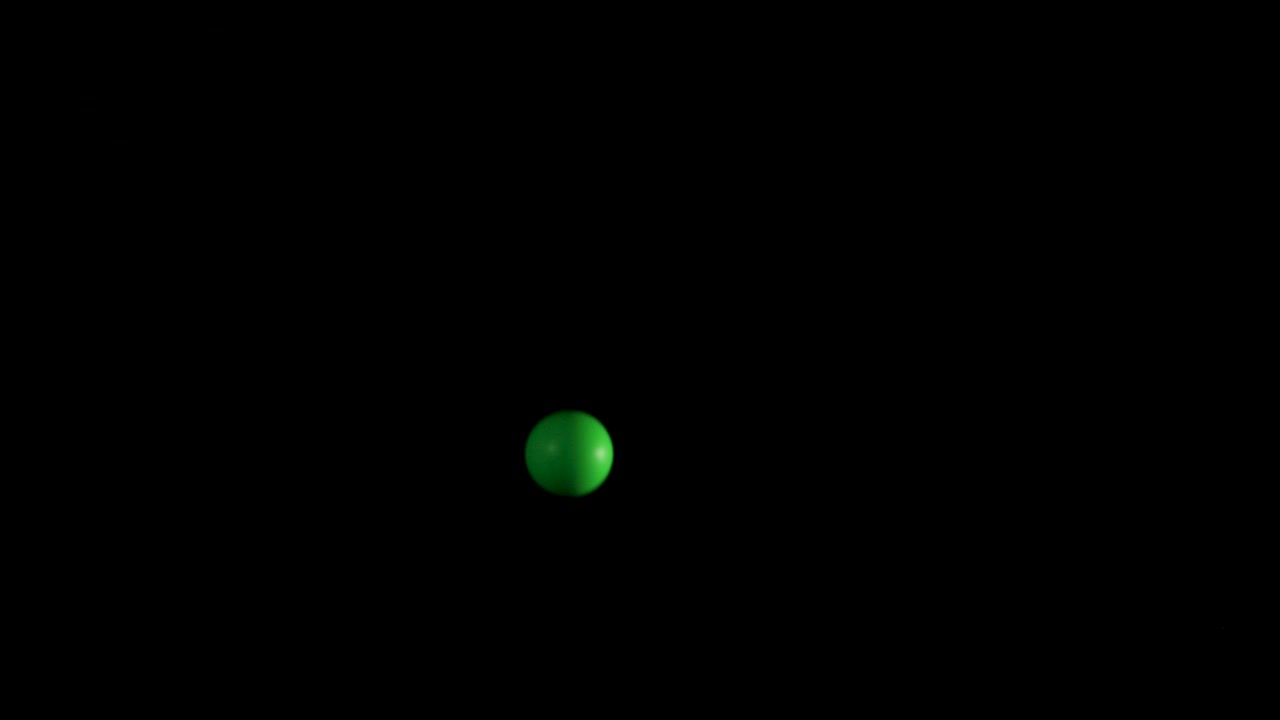 A green ball bounces in a dark space