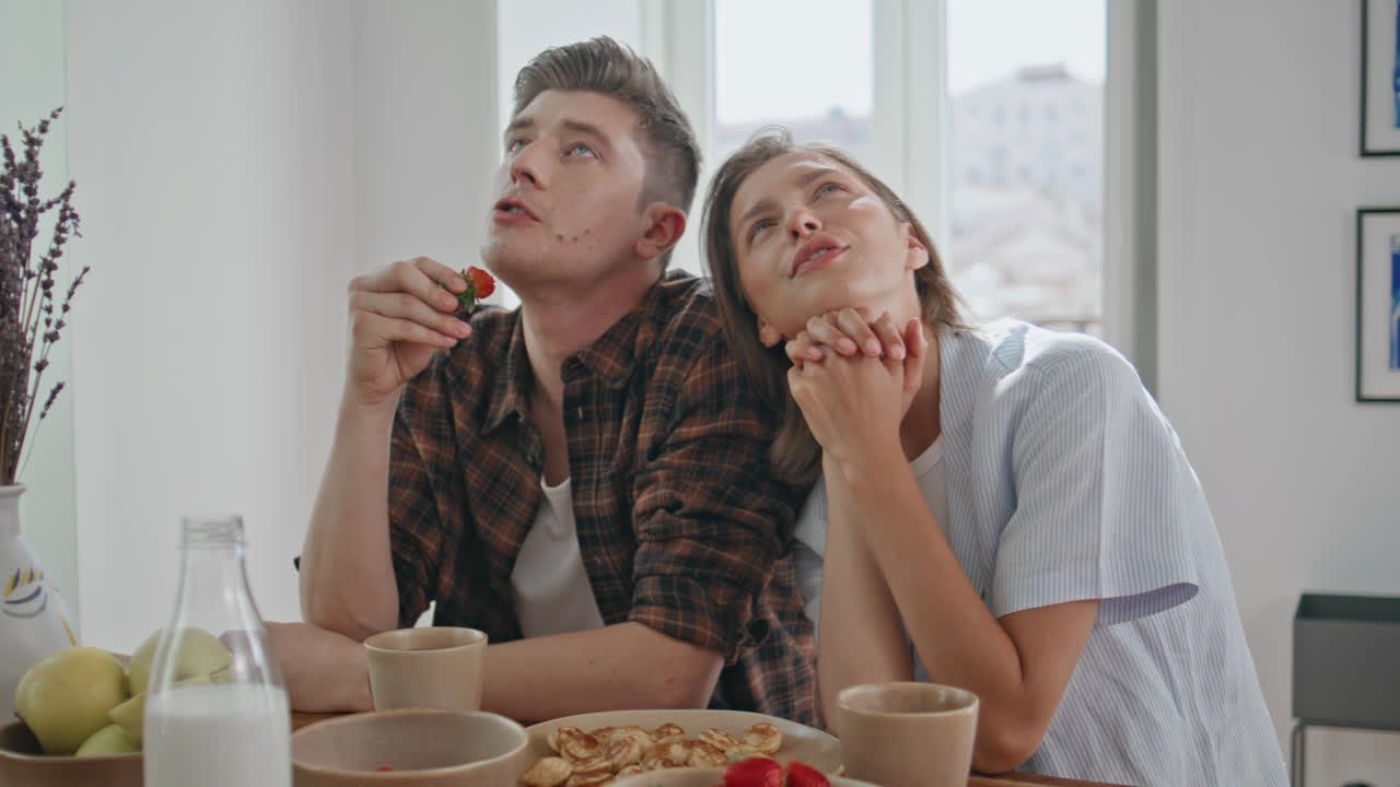 Young family having conversation in kitchen closeup. Lovely couple eat breakfast