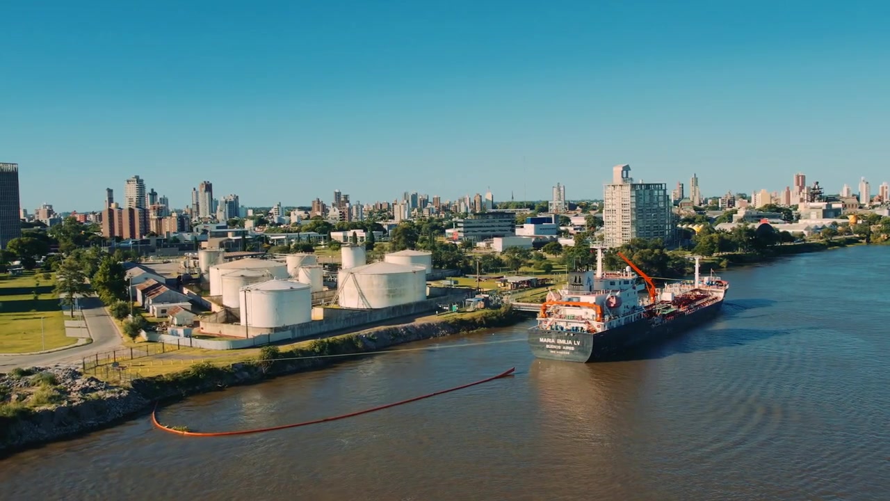 Veduta aerea su un porto petrolifero e una città. Dove una nave sta caricando carburante sul territorio di grandi serbatoi di stoccaggio rotondi per la produzione di carburante industriale in una giornata di sole