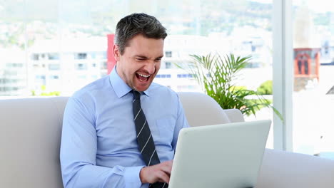 hombre de negocios escribiendo en una computadora portátil sentado en el sofá
