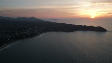 Blauer-Sonnenaufgang-Im-Morgengrauen,-Während-Sich-Sanftes-Goldenes-Licht-über-Die-Küstenstadt-Mit-Meereswellen-Ausbreitet