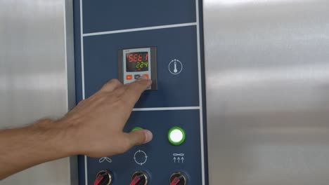 primer plano de manos masculinas ajustando la hora y la temperatura en el panel de control del horno de pan industrial