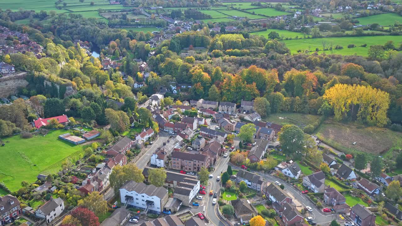 Descending aerial showing clusters of residential houses and gardens bordering tree line at the edge of Knaresborough with a backdrop of rural landscape in North Yorkshire, England