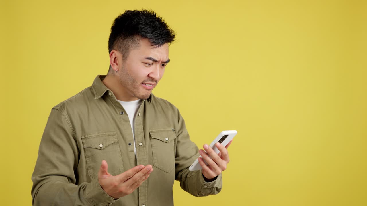 Man looking confused and frustrated while using a smartphone on a yellow background