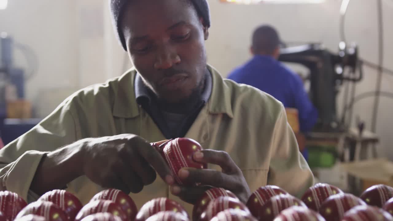 Mixed race man focused on cricket ball in factory