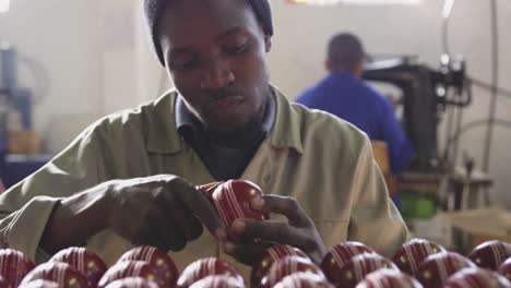 Mixed-race-man-focused-on-cricket-ball-in-factory