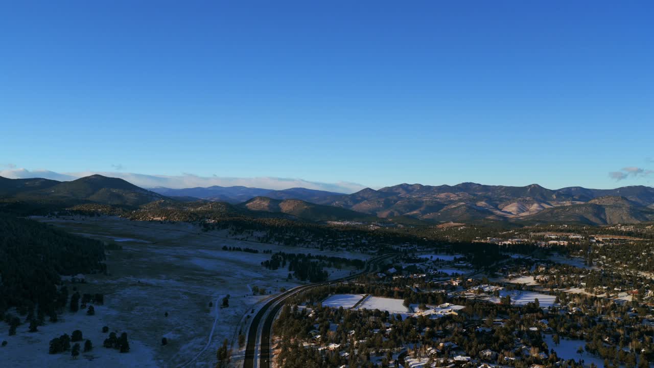 Elk Meadows Bergen Parkway Hiwan Evergreen Colorado aerea drone vento neve pomeriggio soleggiato cielo blu intenso Front Range Montagne Rocciose città auto traffico panoramica verso il basso movimento a sinistra