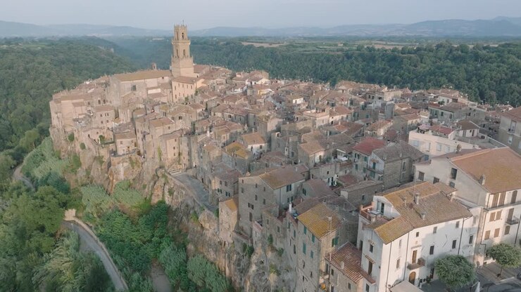 Vista aerea con drone della città medievale collinare di Pitigliano, Toscana, alla luce del mattino, con la Val d'Orcia e vecchi edifici, in 4K.