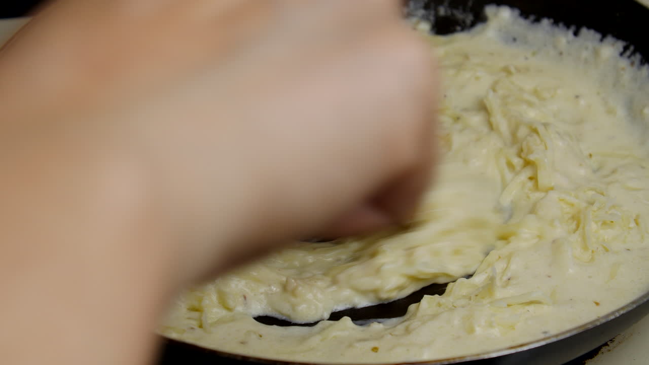 난로에서 집에서 만든 알프레도 소스를 저어주는 사람
