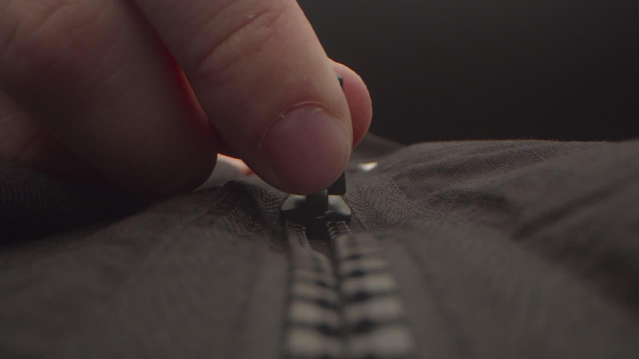 Close up of a hand closing a black zipper