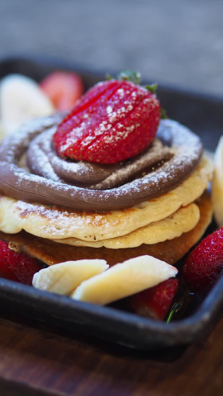 Deliziosi pancake guarniti con cioccolato, fragole e banane