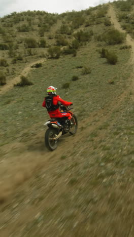 persona en rojo monta motocicleta a lo largo de colinas boscosas fpv. corredor intrépido en casco conduce el vehículo al pico de la montaña en carreras de motocross. deporte extremo en las tierras altas