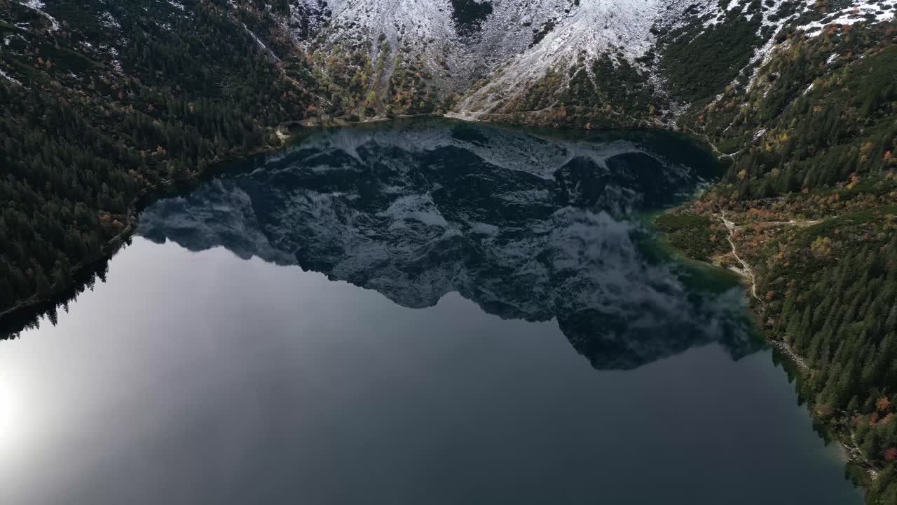 Aerial footage of snowcapped peaks reflected in Morskie Oko Lake in Zakopane Poland