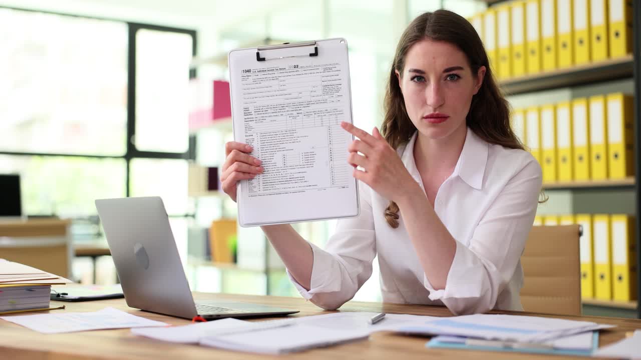 Woman holding tax form in office setting