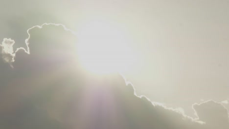 bright sun emerges from behind clouds with light rays, heavenly sky, timelapse