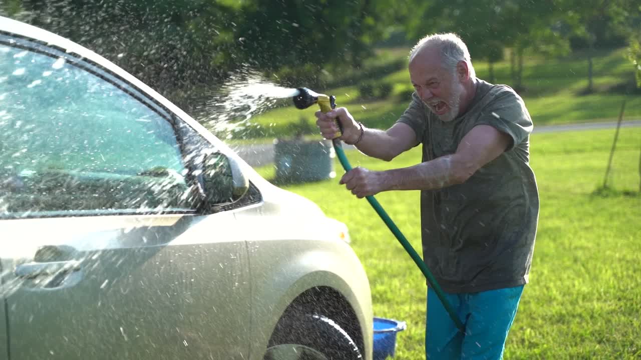 loco con manguera lavando auto y agitando agua en el aire en cámara lenta