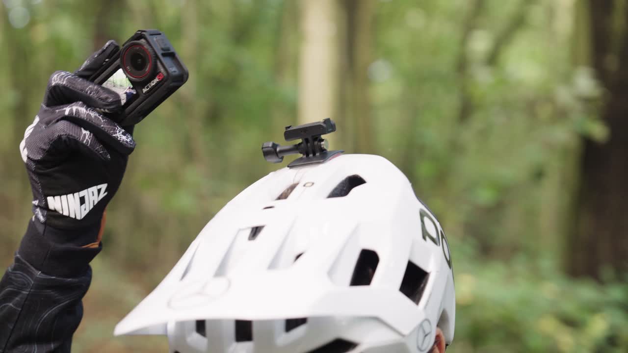 Mountain biker attach action camera on white helmet lock extension, Czechia