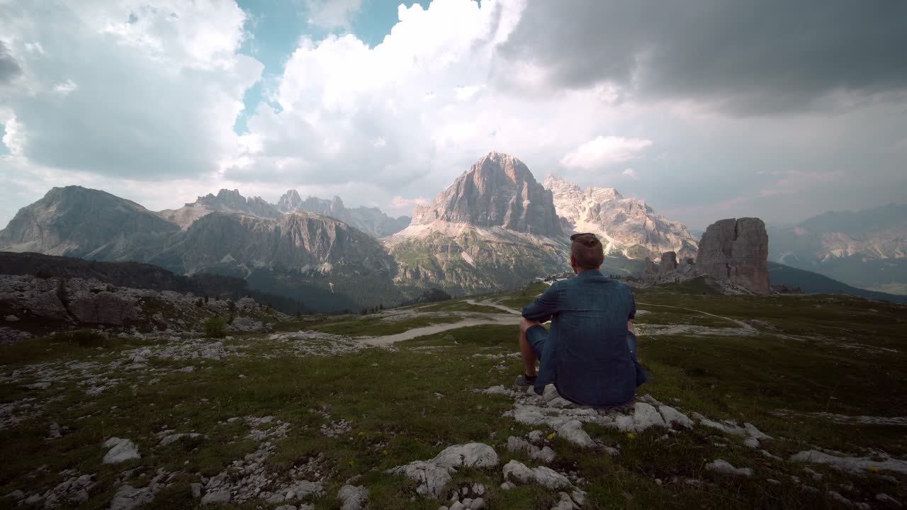 Panorama sulle Dolomiti, escursionista seduto sulla roccia