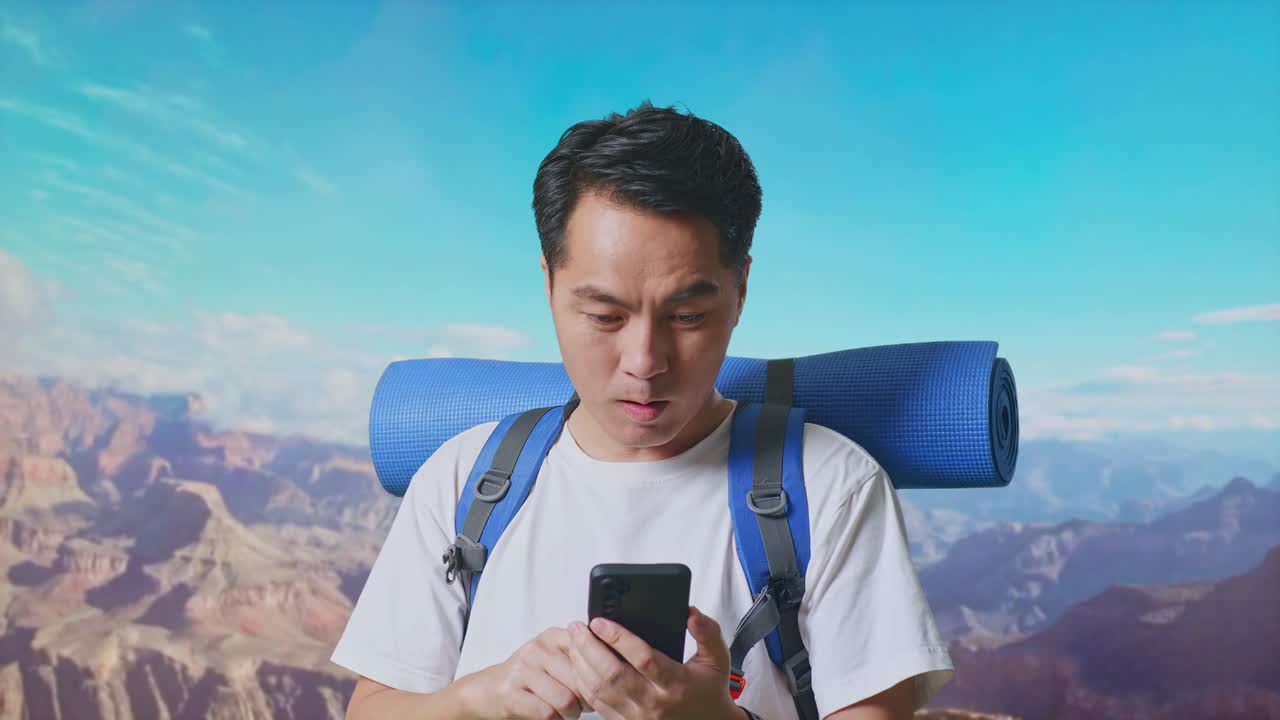 Close Up Of Asian Male Hiker With Mountaineering Backpack Looking At The Smartphone And Saying Wow While Traveling At The Top Of Mountain