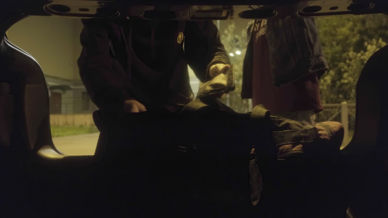 사람들이 밤에 자동차 트크에 가방을 탑재하고 있습니다.