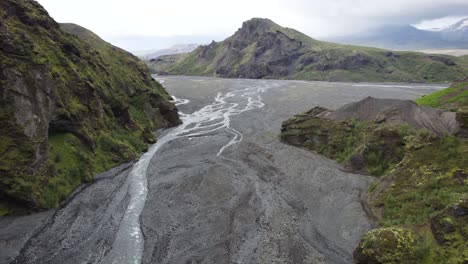 Aerial-dolly-past-ridgeline-and-valleys-above-glacial-braided-river-stream,-thorsmork-iceland