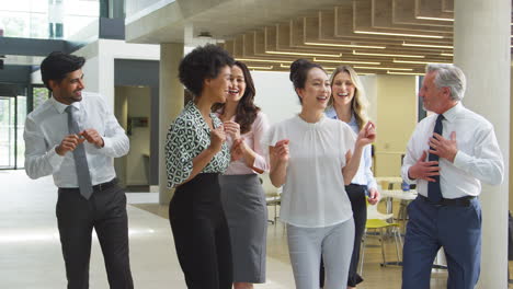 smiling multi-cultural business team having fun and dancing in office lobby