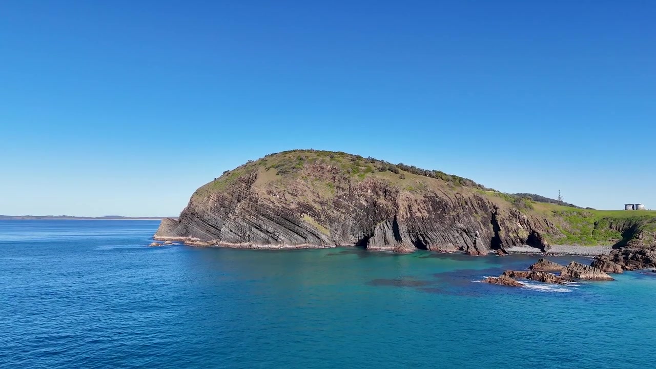 Ripresa con drone dell'acqua turchese dell'Oceano Pacifico che incontra scogliere rocciose a Crescent Head, Australia.
