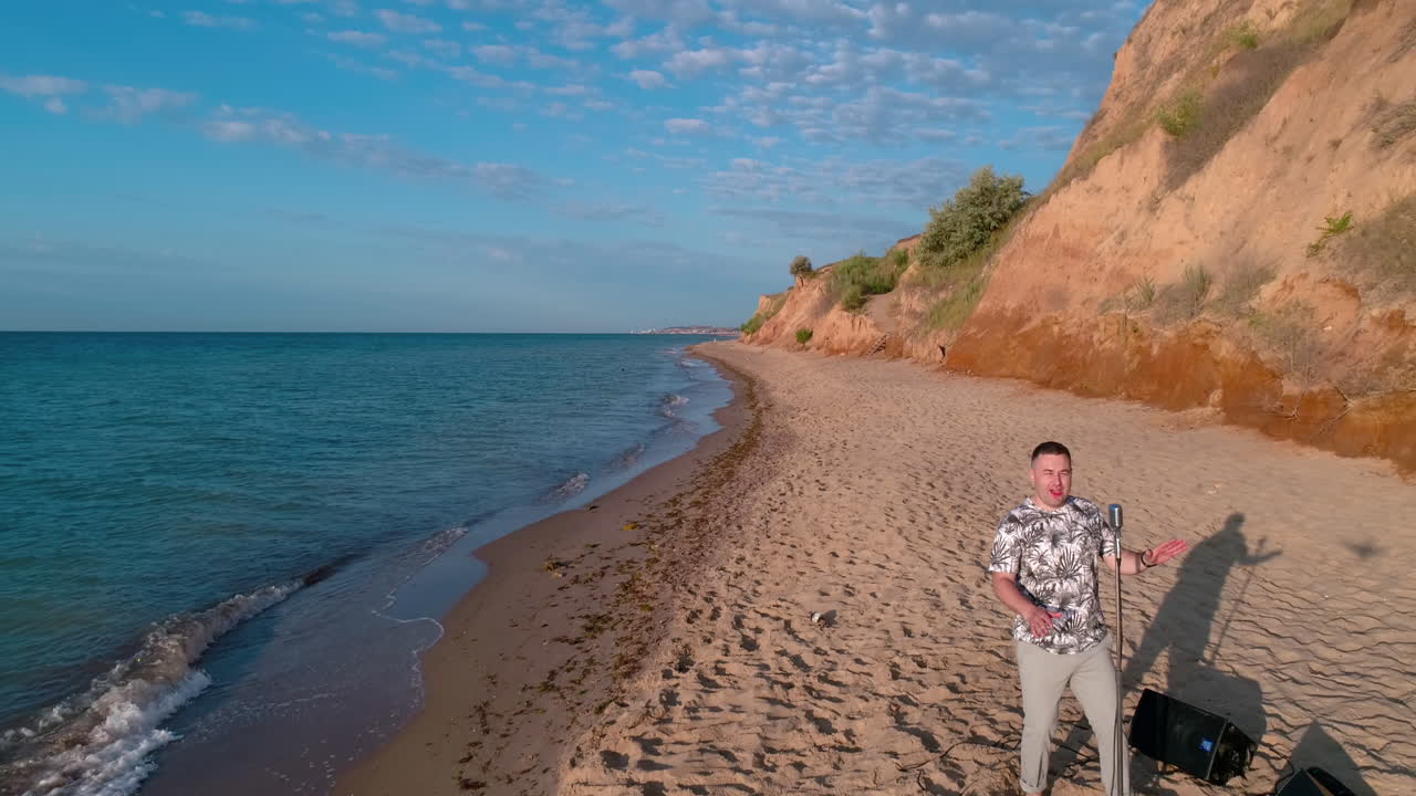 Talented Man Sing Song Into Microphone. Aerial view of man singing song at concert on the beach