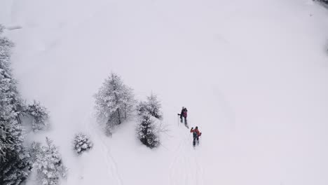 couple walks across a snowy field in snowshoes, as the drone pans around them and flies up