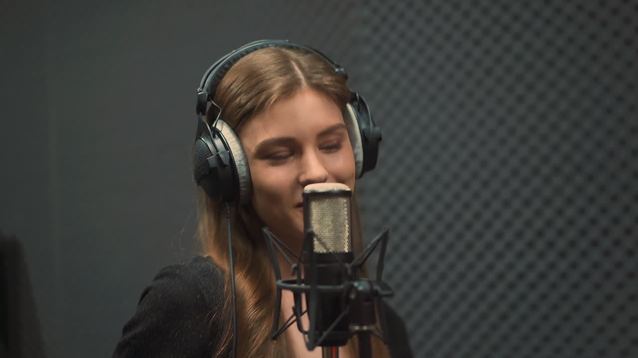 Giovane donna canta una canzone popolare con il microfono in studio