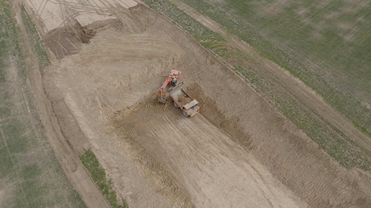 Luftfoto af byggeplads med gravemaskine og dumper
